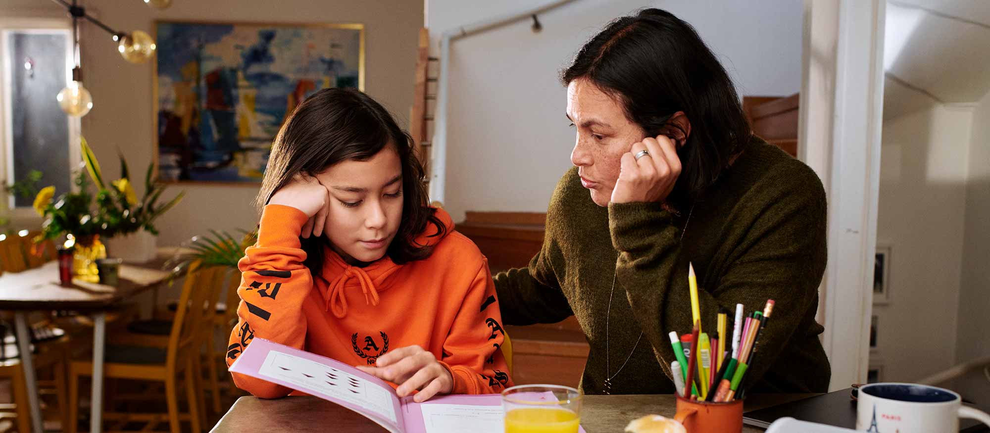 Mamma hjälper tonåring med läxorna hemma 
