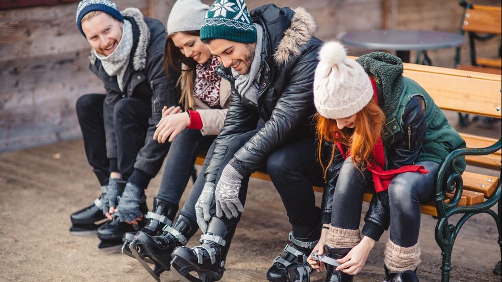 People sitting on a bench putting on skates 